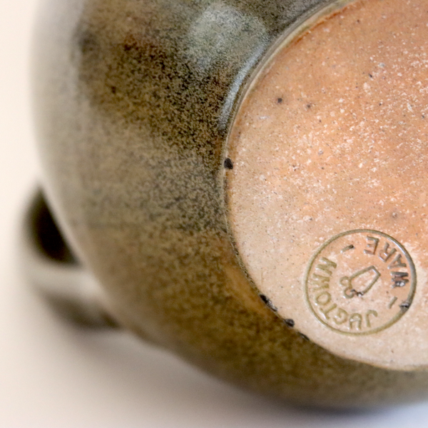 Close-up of a ceramic mug with a brand logo on a beige background