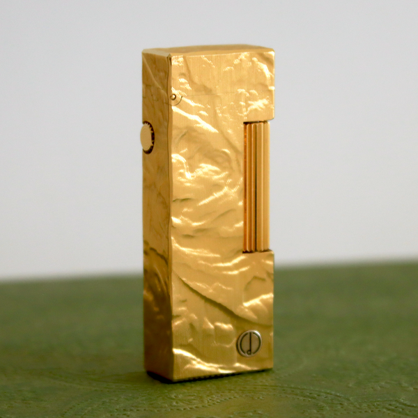 Gold lighter on a green surface with a gray background
