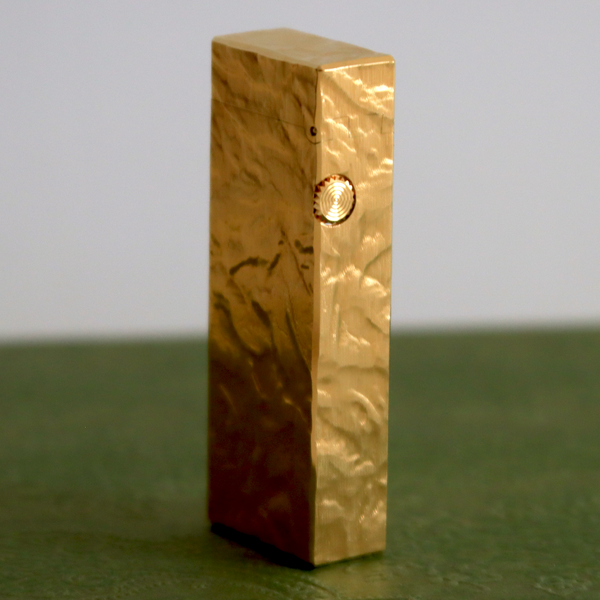 Gold rectangular object on a green surface with a gray background